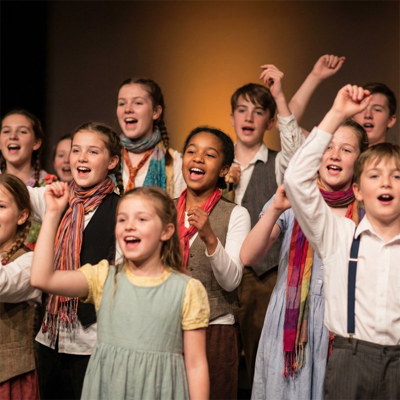 Young performers dancing together on stage at the Academy