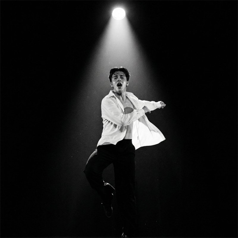 A young performer standing in a spotlight on stage